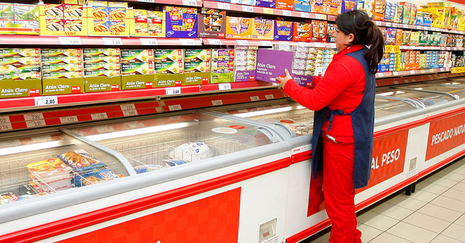 Una empleada de DIA colocando conservas en un supermercado.